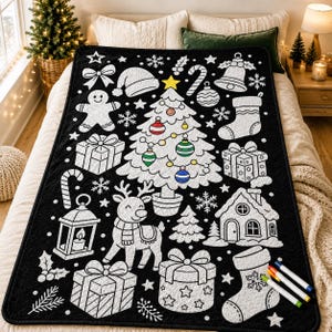 May include: A black throw blanket featuring a white outline pattern of Christmas icons including a central tree with colorful ornaments, a reindeer, gingerbread person, gifts, stockings, a lantern, and a house, accompanied by four markers.