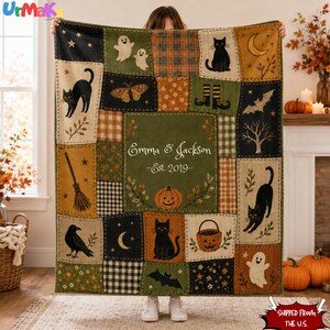 May include: A rectangular throw blanket featuring a patchwork design with Halloween motifs including black cats, ghosts, bats, pumpkins, a broom, and a moth. The center panel is olive green with the text Emma & Jackson Est. 2019 in white script.