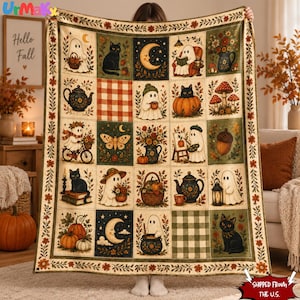 Op de afbeelding: Een rechthoekige plaid met een raster van illustraties, waaronder geesten, zwarte katten, pompoenen, paddenstoelen, theepotten en maansikkels. Het ontwerp bevat herfstthema's zoals bloemstukken, eikels en ruitpatronen.