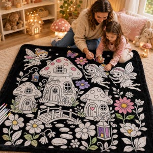 May include: A black plush blanket featuring a white line art design of fairy tale mushroom houses, winged fairies, flowers, and a stone bridge. The pattern includes a large central mushroom house, smaller mushroom dwellings, and various floral elements, all outlined in white on a dark background.