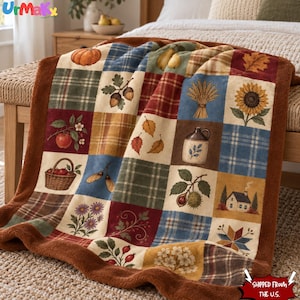 Pode incluir: Uma manta de pelúcia com um design de patchwork apresentando ilustrações com tema de outono, incluindo abóboras, girassóis, maçãs, bolotas, trigo, uma pequena casa e padrões xadrez, contornada por uma borda felpuda marrom.