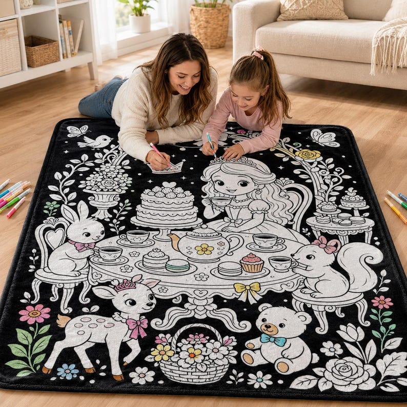 May include: A black rectangular blanket featuring a white line art illustration of a tea party scene with a princess, a rabbit, a squirrel, and a bear. The design includes a table with a teapot, cake, and teacups, surrounded by floral motifs.