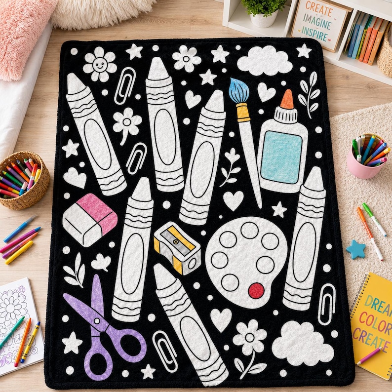 May include: A rectangular black blanket featuring a white outline pattern of art supplies including crayons, a paintbrush, a glue bottle, a pencil sharpener, a paint palette, scissors, an eraser, paper clips, flowers, stars, and clouds.