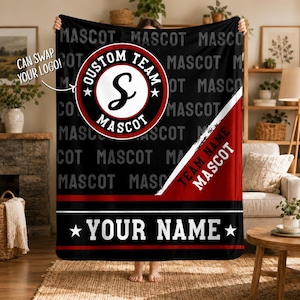 May include: A black fleece blanket featuring a repeating grey MASCOT text pattern, a central circular logo with the text CUSTOM TEAM MASCOT and a large letter S, a diagonal red stripe with TEAM NAME MASCOT text, and a bottom red stripe with YOUR NAME.