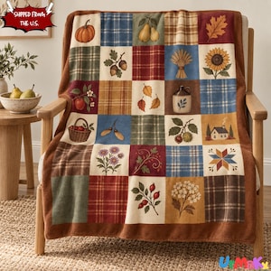 May include: A patchwork throw blanket featuring a grid of squares with autumn-themed illustrations including pumpkins, pears, acorns, wheat, sunflowers, a basket of apples, a small house, and various leaves, all bordered by a solid brown trim.