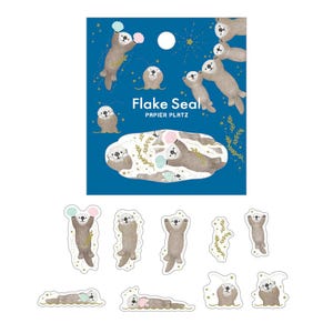 May include: A sheet of stickers featuring illustrations of otters with cotton candy and the text "Flake Seal, Papier Platz" on a blue background. Additional individual otter stickers are also included.