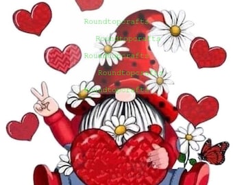 May include: A red gnome with a white beard and a red hat with white polka dots holds a large red heart. The gnome is surrounded by white daisies and red hearts. The gnome is wearing blue jeans and red boots. The gnome is giving the peace sign with one hand.