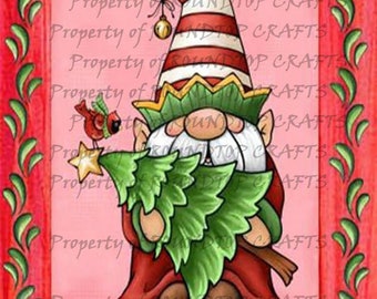 May include: A Christmas gnome with a red and white striped hat holds a small green Christmas tree. The gnome is wearing a red and green outfit and has a white beard. A red cardinal sits on a branch of the tree.