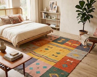 May include: A colorful, rectangular area rug with a patchwork design. The rug features squares of various colors, including yellow, orange, green, and pink, with geometric and tribal-inspired patterns. The rug is fringed on the edges and is placed in a bedroom setting.