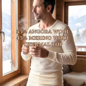 May include: Cream-coloured thermal top made of 55% Angora wool and 45% Merino wool. The long-sleeved shirt is worn by a person holding a cup near a window. The text "55% ANGORA WOOL 45% MERINO WOOL THERMAL TOP" is displayed.