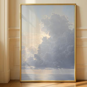 May include: A vertical rectangular wall art print featuring a serene seascape with soft, voluminous clouds illuminated by a gentle golden light. The artwork is encased in a thin, polished gold metal frame, capturing a calm horizon over water.