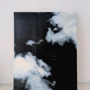 Könnte beinhalten: Quadratische Leinwandkunst mit einer dramatischen Wolkenlandschaft. Das Kunstwerk wird von einem tiefschwarzen Hintergrund dominiert, der durch flauschige weiße und hellgraue Wolkenformationen kontrastiert wird. Das Gemälde erzeugt Tiefe und Atmosphäre.