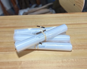 May include: A stack of rolled, clear plastic tubes, secured with rubber bands. The tubes have the text "NORTHWEST WILLOW" printed on them. The tubes are on a light brown wooden surface.