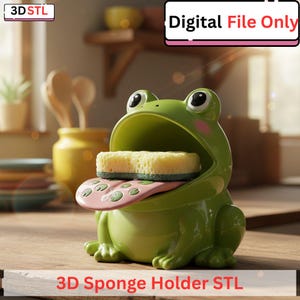 Op de afbeelding: Een groene kikker-vormige spons houder met een spons erin. De kikker heeft grote ogen, roze wangen en een roze tong met groene stippen. De tekst "3D Sponge Holder STL" staat onderaan en "Digital File Only" bovenaan.