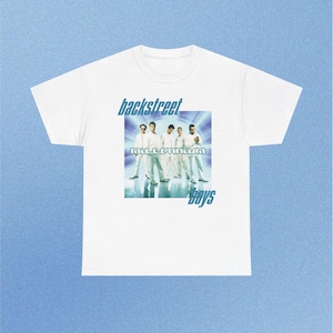 Puede incluir: Una camiseta blanca de manga corta con un estampado gráfico de los Backstreet Boys en la parte delantera. El diseño incluye el texto "backstreet" sobre el grupo, "millennium" en el centro y "boys" debajo, todo en una fuente de color azul.