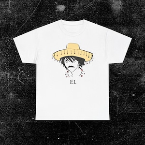 May include: A white short-sleeve t-shirt featuring a graphic illustration of a character with dark hair and a mustache wearing a light yellow sombrero. Below the illustration, the text EL is printed in a simple black serif font.