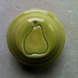 May include: A green ceramic dish with a raised design of a pear in the center.