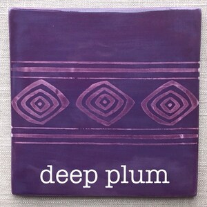 May include: A deep plum colored ceramic tile with a geometric pattern of concentric squares in a lighter shade of purple. The tile has the words "deep plum" written in white text at the bottom.