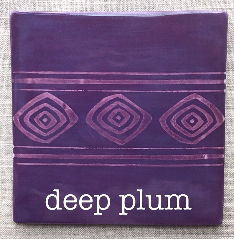 May include: A deep plum colored ceramic tile with a geometric pattern of concentric squares in a lighter shade of purple. The tile has the words "deep plum" written in white text at the bottom.