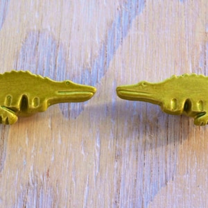 May include: Two ceramic alligator figurines facing each other. The alligators are a bright yellow-green color.