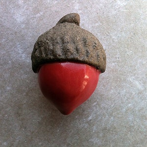 Peut inclure: Une décoration d'écureuil en céramique avec un chapeau brun et un corps rouge.