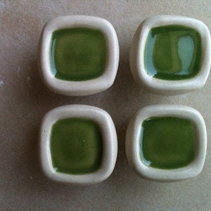 May include: Four square ceramic dishes with a white rim and a green glaze inside.