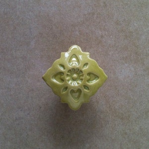 May include: A green ceramic cabinet knob with a decorative floral design.