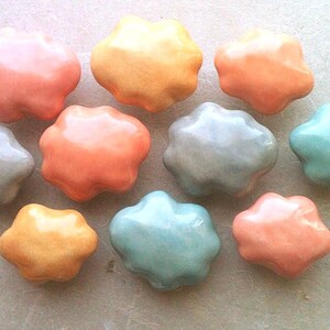May include: Ten ceramic flower-shaped knobs in various shades of pink, blue, and yellow. The knobs have a glossy finish and are perfect for adding a touch of whimsy to furniture.