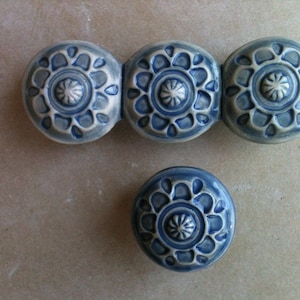 Puede incluir: Cuatro azulejos de cerámica azul y blanco con un patrón floral decorativo. Los azulejos están dispuestos en una fila con un azulejo debajo de la fila.