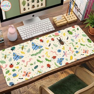 May include: A rectangular desk mat featuring a cream-colored background with a repeating pattern of colorful insects, including blue butterflies, red ladybugs, green beetles, pink worms, and yellow bees, interspersed with small green leaves and blue flowers.