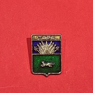 May include: A rectangular pin with a gold border and a red background. The pin features a blue top section with gold text reading "TAPA" and a green bottom section with a silver animal silhouette.