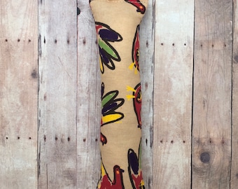 May include: A beige cat toy with a colorful bird pattern. The toy is shaped like a long, thin pillow.