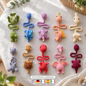 May include: A collection of ten crocheted dinosaur bookmarks in various colors including green, blue, purple, orange, cream, gray, tan, red, pink, and maroon. Each bookmark features a head and body connected by a long, thin, winding tail.