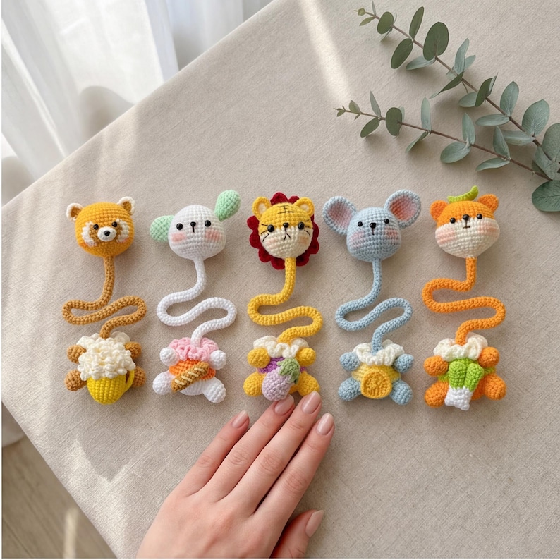 Pu&ograve; includere: Una collezione di cinque giocattoli di animali all'uncinetto fatti a mano. Ogni giocattolo presenta una testa di animale diversa, tra cui un orso, un coniglio, un leone, un topo e una volpe, collegata a uno stelo ondulato e a una base decorativa. I giocattoli sono in vari colori, tra cui giallo, bianco, arancione e blu.