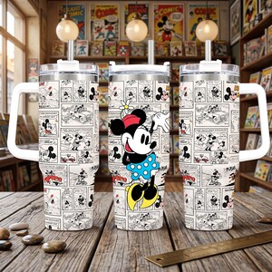 May include: A stainless steel tumbler with a handle and straw, featuring a black and white comic strip pattern of Mickey Mouse and Minnie Mouse. The center tumbler displays a large, colorful illustration of Minnie Mouse wearing a blue polka dot skirt.