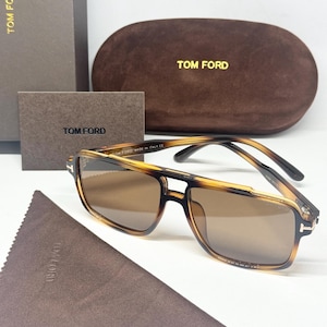 May include: Tom Ford sunglasses featuring a brown tortoise shell frame with a double bridge design and brown tinted lenses. The set includes a brown velvet hard case, a brown box, a small informational card, and a brown microfiber cleaning cloth.