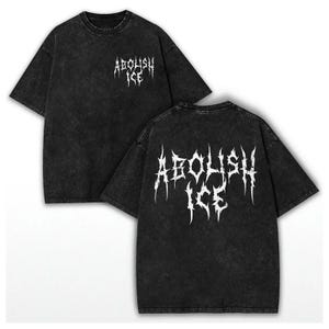May include: Two views of a black, short-sleeved t-shirt with the words "ABOLISH ICE" printed in white, gothic-style lettering. The shirt has a faded, distressed appearance. The same text is printed on the front and back of the shirt.