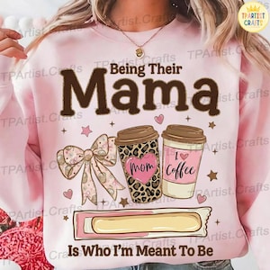 Könnte beinhalten: Hellrosa Sweatshirt mit dem Text "Being Their Mama" in braunen Buchstaben. Das Design umfasst Kaffeetassen, eine Schleife, Herzen und die Texte "Mom" und "I love Coffee".