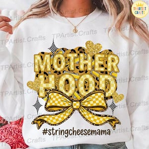 May include: White sweatshirt with a graphic design featuring the word "MOTHERHOOD" in yellow and black checkered letters. The design includes a bow, hearts, and the hashtag #stringcheesemama.