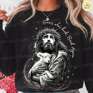 May include: Black sweatshirt featuring a detailed black and white graphic of Jesus wearing a crown of thorns and holding a lamb. The text "Guess who's back, Back Again" is written in white. The sweatshirt has a crew neck.