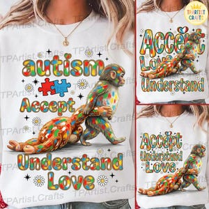 以下が含まれることがあります： カラフルなグラフィックが特徴の白いスウェットシャツ。2匹の猿、パズルのピース、そして「自閉症」、「受け入れる」、「理解する」、「愛」という言葉が描かれています。デザインにはデイジーと星が含まれています。