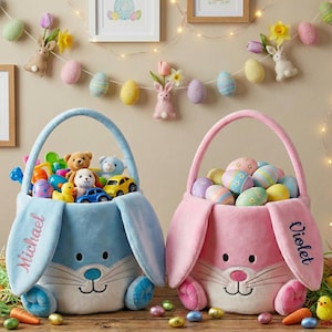 May include: Two plush Easter baskets shaped like bunnies, one blue and one pink, filled with toys and decorated eggs. The blue basket has "Michael" embroidered on the ear, and the pink basket has "Violet". Easter decorations include felt eggs, bunnies, and string lights.