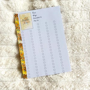 May include: A white notepad with a floral border and the text "Solution Colo." The notepad has a series of checkboxes and lines for notes. The floral border is yellow with brown and orange flowers.