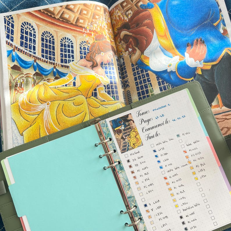 May include: Open coloring book page featuring a yellow gown and a blue suit. A green planner with a teal page and handwritten notes is in the foreground. The text "Tome: princesses 2" is visible.