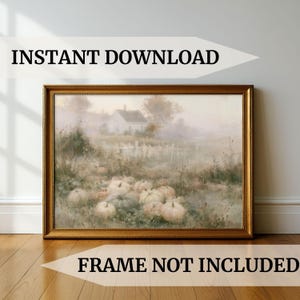 May include: A rectangular wall art print in a gold frame featuring a muted, hazy landscape painting of a pumpkin patch with several pale orange and white pumpkins in the foreground, a white house, and a fence in the background. Text reads INSTANT DOWNLOAD.
