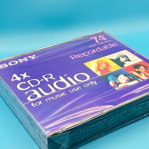 May include: A sealed Sony 4x CD-R audio disc pack with a purple cover featuring the text 74 color collection Recordable and for music use only. The packaging includes a collage of four small photographs showing different people in various settings.