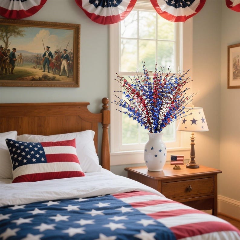 Op de afbeelding: Een slaapkamer ingericht met patriottische thema's. Een bed heeft een kussen en deken met de Amerikaanse vlag. Een witte vaas met steraccenten bevat rode, witte en blauwe stervormige bloemstelen. Een lamp met een sterrenpatroon staat op een houten nachtkastje.