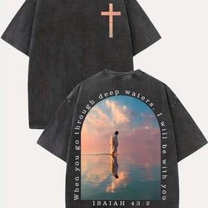 May include: Dark gray t-shirt with a cross graphic on the front. The back of the shirt features a religious image of a person standing in water with the text "When you go through deep waters, I will be with you. Isaiah 43:2."