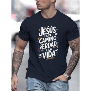 May include: Navy blue crew neck t-shirt with the text "Jesús es el Camino, la Verdad y la Vida" in white, yellow, and red. The text is from John 14:6. The shirt is a solid color.