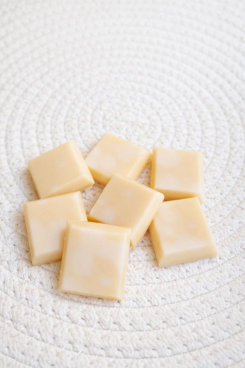 Pode incluir: Oito pastilhas de cera quadradas, amarelo claro, dispostas sobre uma superf&iacute;cie branca texturizada. As pastilhas de cera t&ecirc;m um aspeto liso e brilhante. O conjunto sugere um produto de ambienta&ccedil;&atilde;o para a casa, possivelmente para um queimador de &oacute;leos. O aspeto &eacute; simples.